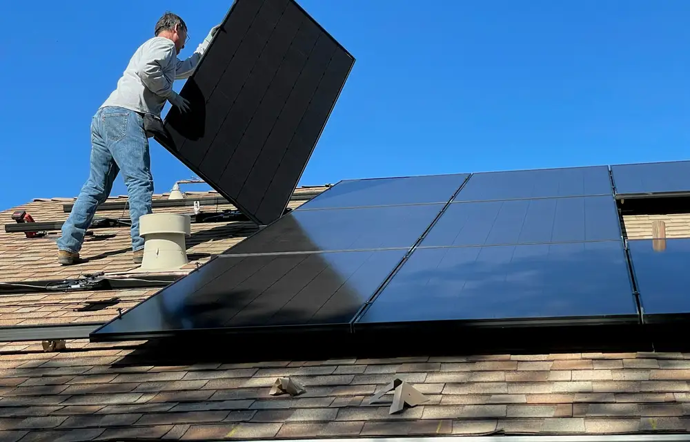 An installer fitting a solar panel onto a roof
